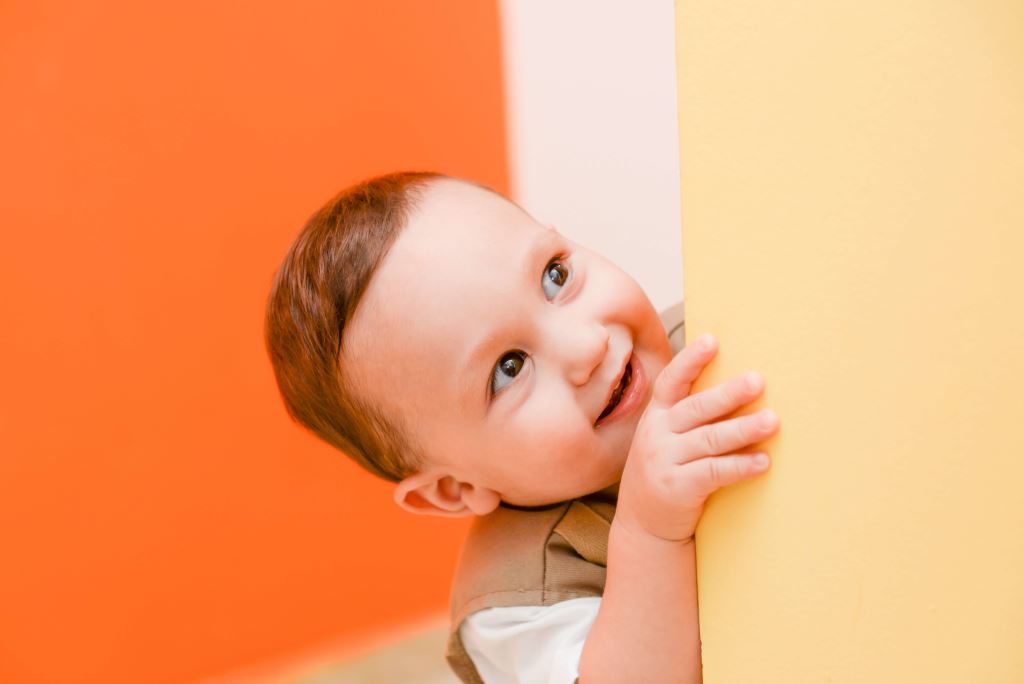 Petit garçon souriant passant la tête au détour d'un mur.